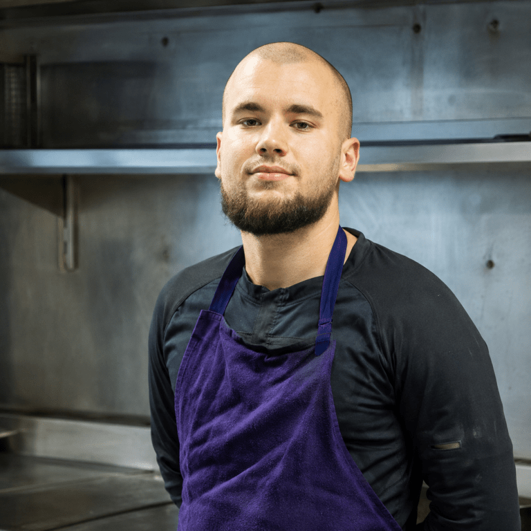 Jeune chef cuisinier posant dans les cuisines professionnelles d'un restaurant à Vitry-sur-Seine