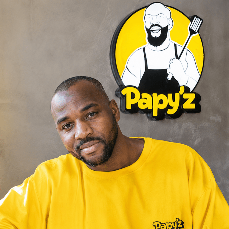 Portrait du gérant de Papy'z devant l'enseigne du restaurant, spécialisé en cuisine africaine et plats faits maison.
