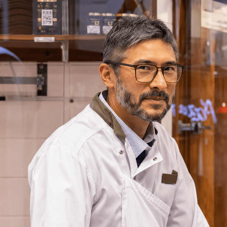 Commerçant artisan souriant dans sa boutique à Vitry-sur-Seine, illustrant le savoir-faire et la proximité du commerce local.