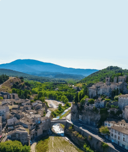 Vue aérienne du village médiéval de La Romaine en Provence, avec son pont de pierre, sa rivière et son château perché.