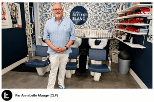 Le gérant du Salon Bleu & Blanc pose dans son salon de coiffure moderne, devant les bacs de lavage. Photo : Annabelle Maugé (CLP).