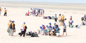 Groupe d'enfants et d'accompagnateurs sur une plage des Hauts-de-France dans le cadre d'un séjour organisé par l'association Vacances Ouvertes, soutenue par la Région.
