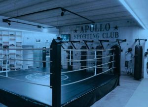Salle de boxe de l’Apollo Sporting Club avec ring et sacs de frappe.