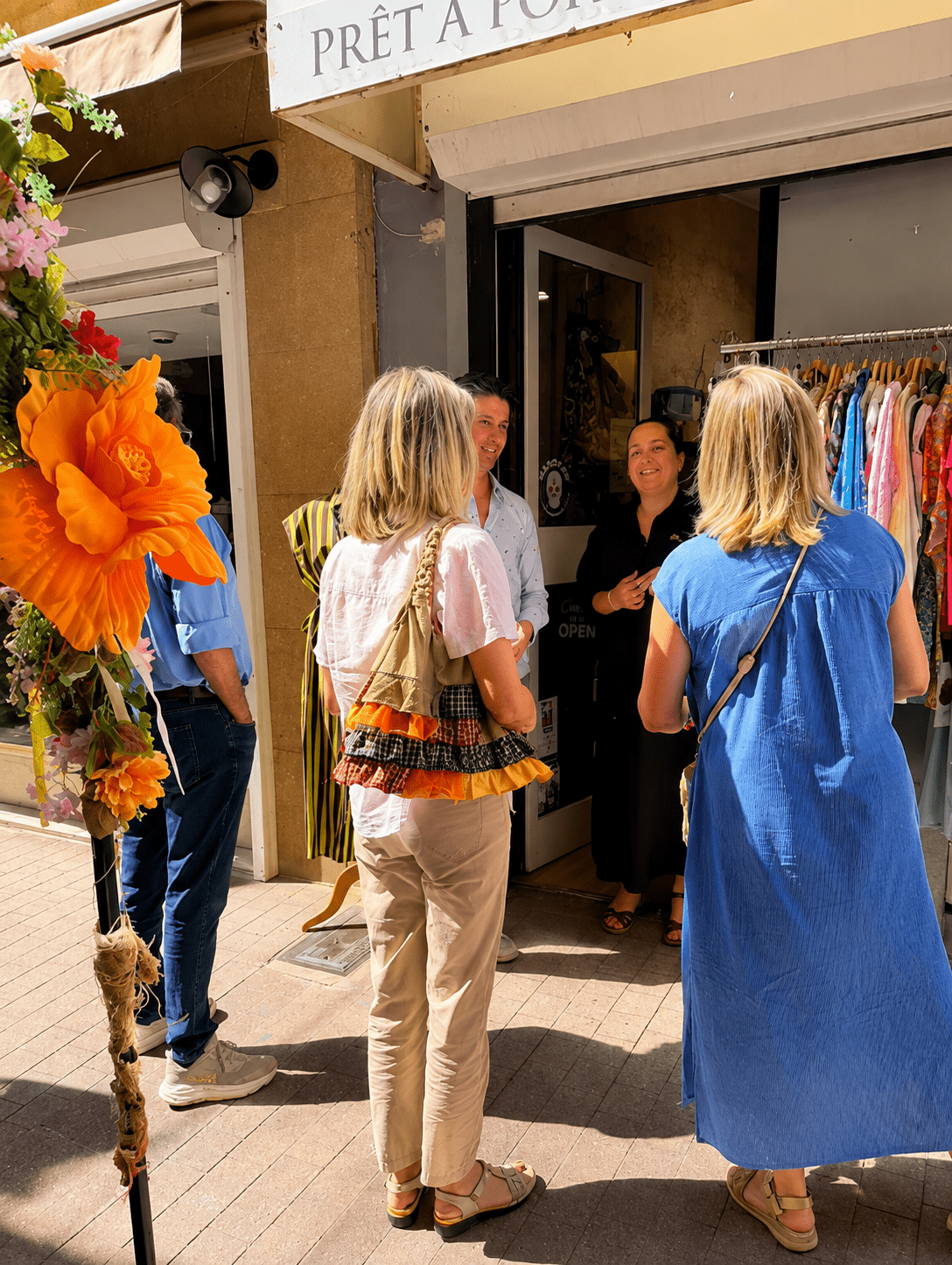 Clients et commerçants échangent devant une boutique de prêt-à-porter