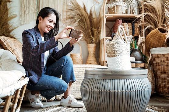 Commerçante photographiant des articles de décoration artisanale pour développer la visibilité de sa boutique sur Internet.
