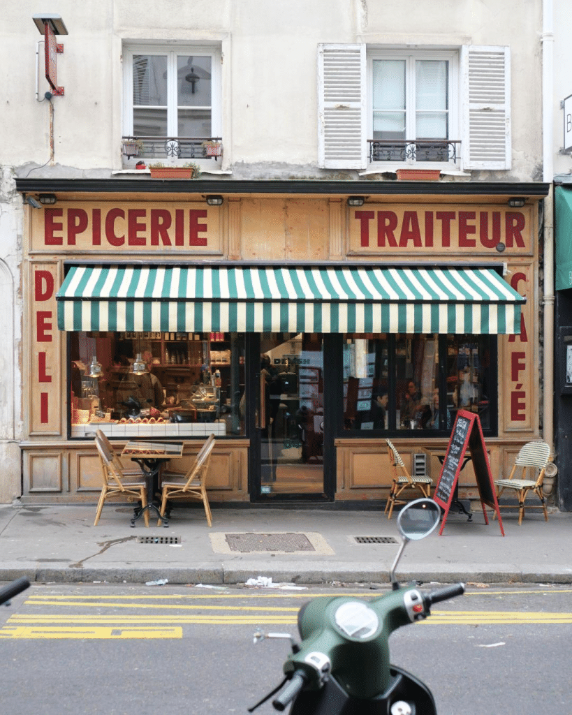 Devanture d’une épicerie-traiteur indépendante avec vitrine alimentaire et terrasse.