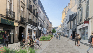 Rue piétonne commerçante avec boutiques, terrasses et espaces végétalisés dans un centre-ville français.