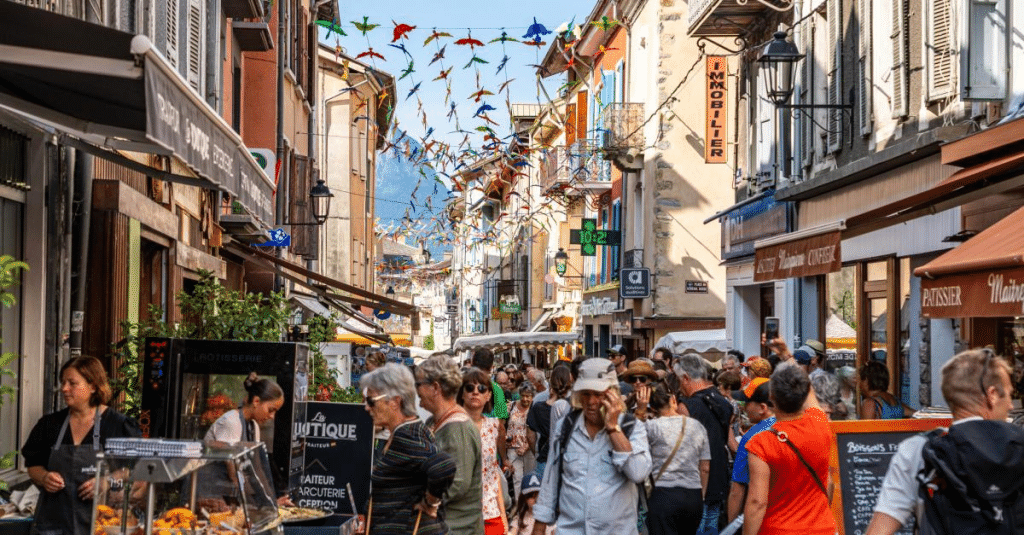 Rue commerçante animée avec de nombreux piétons, boutiques de proximité et décorations colorées dans le centre-ville.
