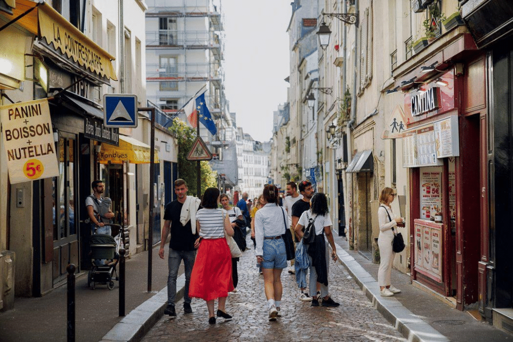 Rue commerçante bordée de boutiques et de restaurants avec des piétons en centre-ville.
